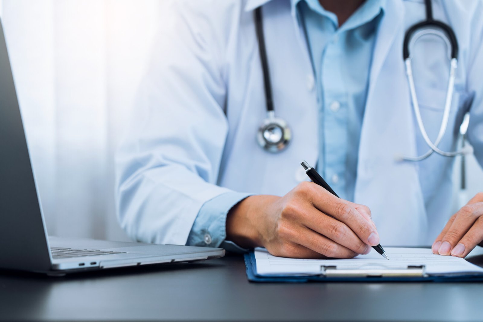 Doctor hand holding pen writing patient history list on clipboar