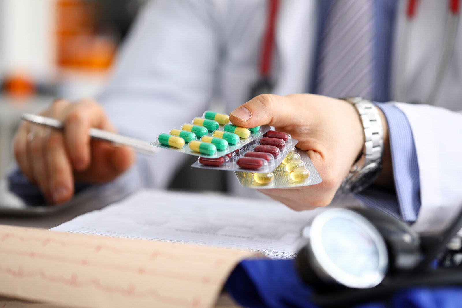 GP in clinic holding pack of different blisters
