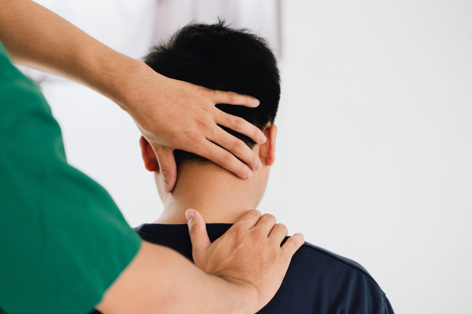 physiotherapist massage therapist holding male client's head and